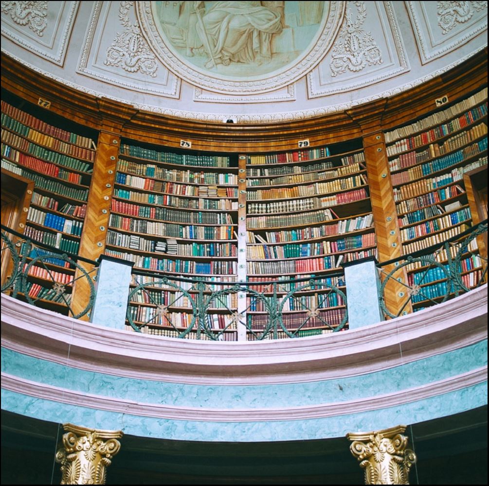 Upwards view of curved bookcase in large library
