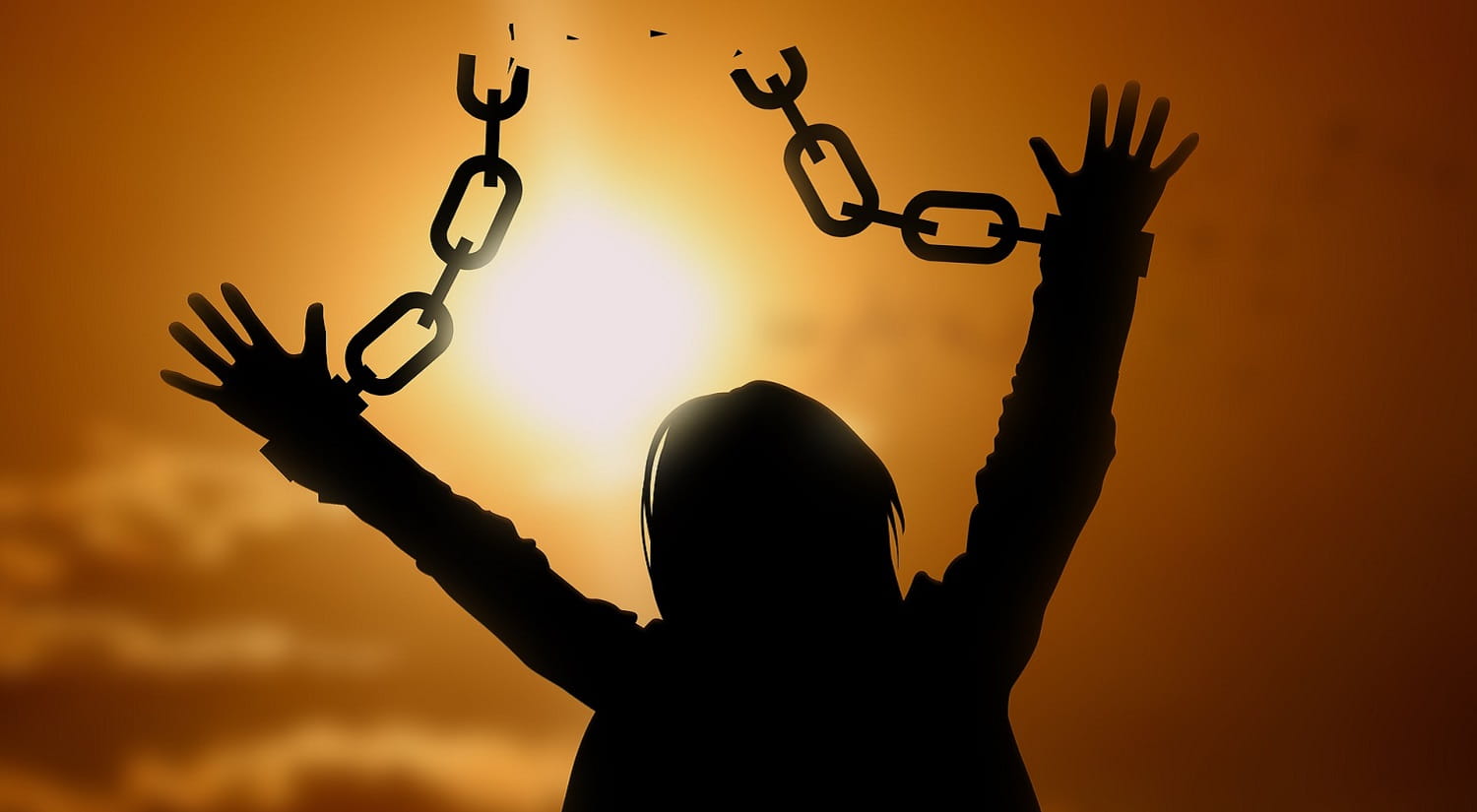 A person with chains breaking free, with the sun in the background, representing freedom.