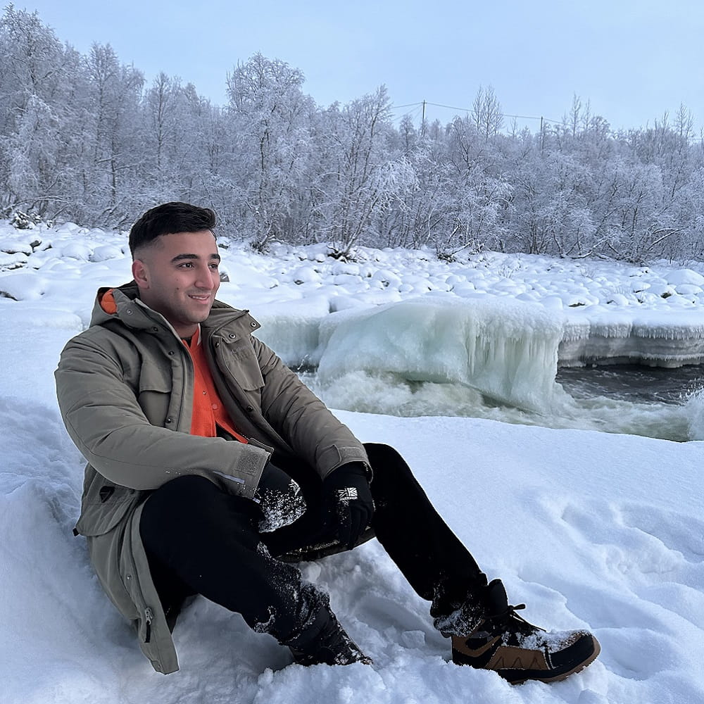 student sitting in snow in Finland