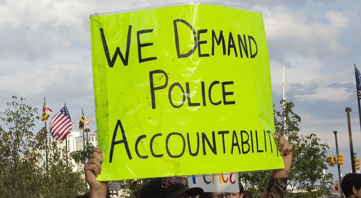 A protestor holding up a sign for police accountability on racism.