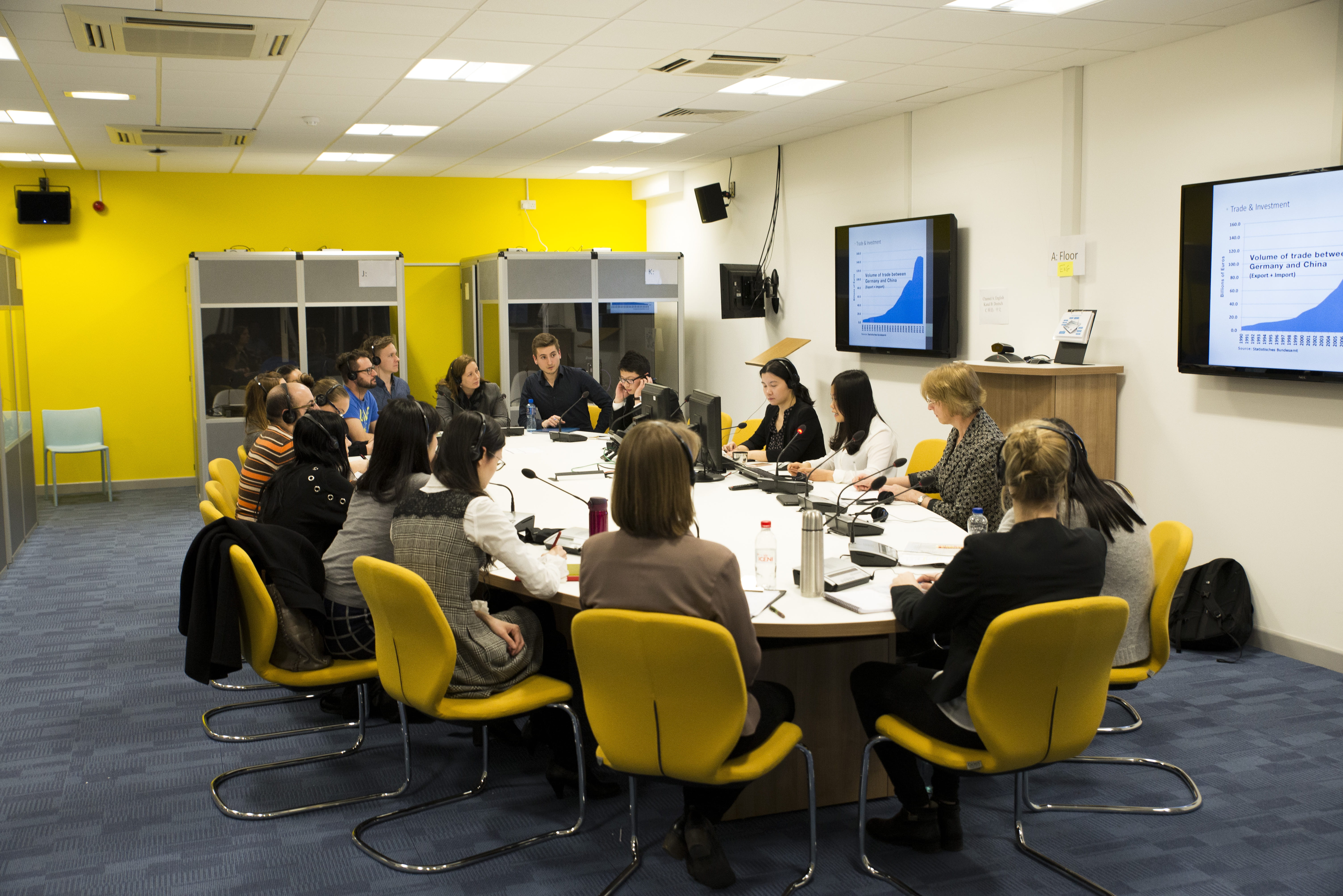 Students taking part in a mock conference within our interpreting lab - students sitting around a round table, with microphones and interpreting equipment