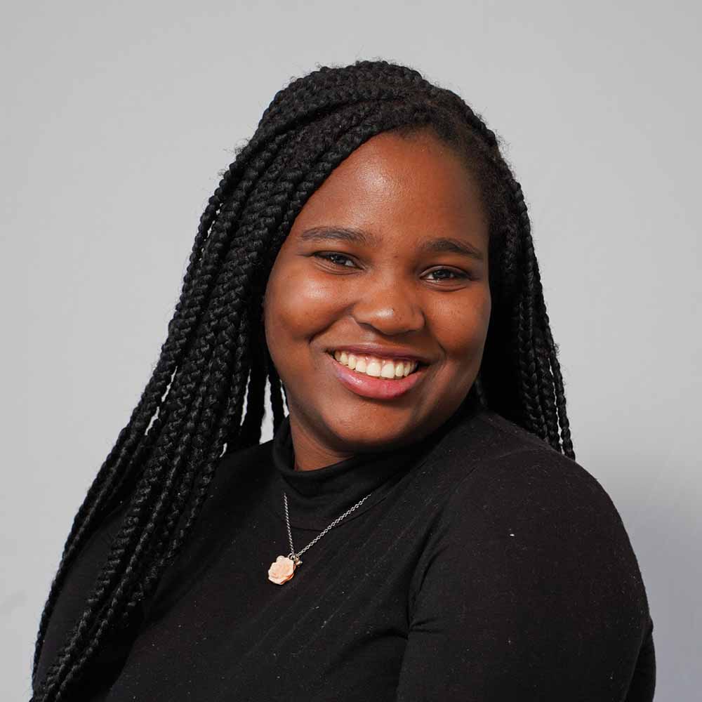 Stephanie Agha, a young black woman is smiling and wearing a black top