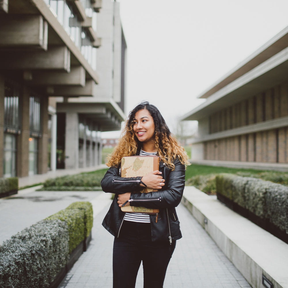 Student holding books next to the library at Colchester Campus