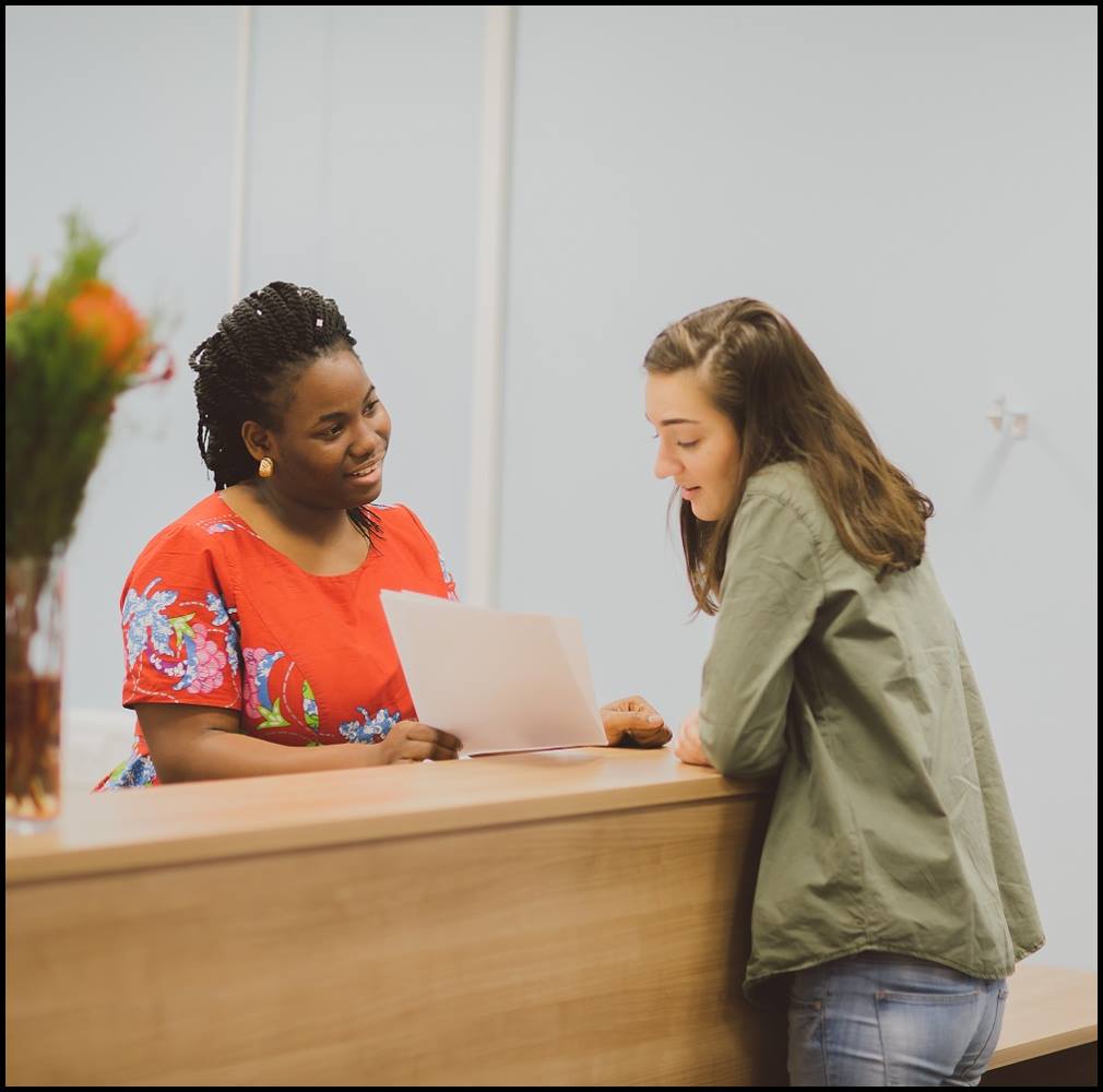 Two people talking and smiling, stood by a counter