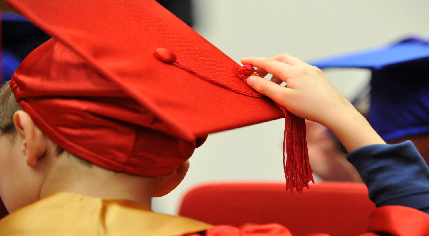 Close up shot of back of young boy's red mortar board 