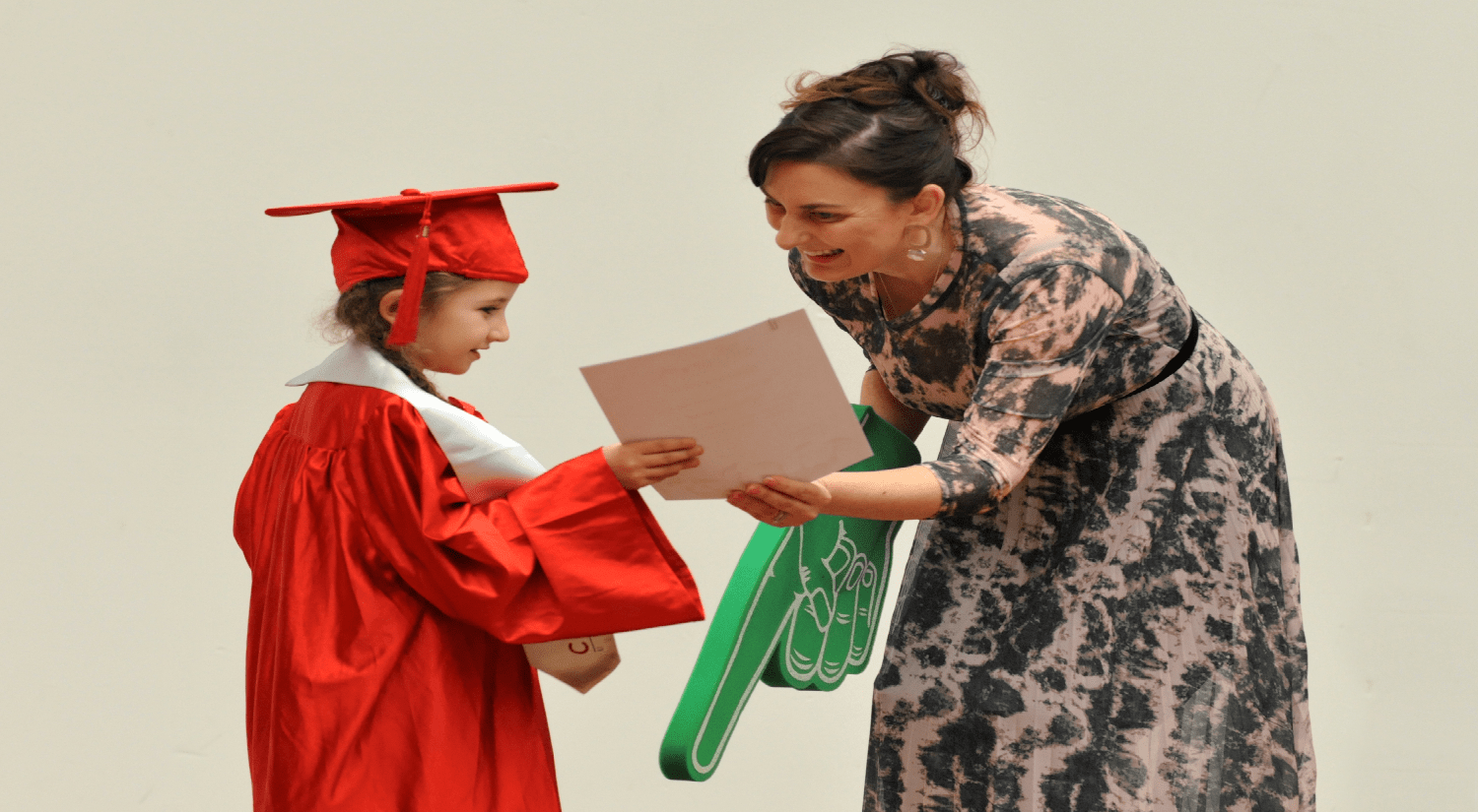 Young girl in red gown receiving her children's university graduation certificate from the organiser