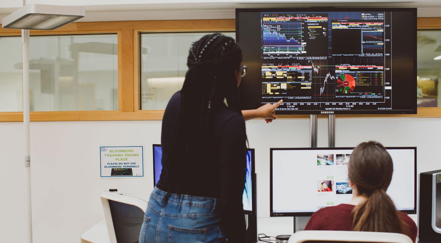 Two students look at a screen in the virtual trading lab)