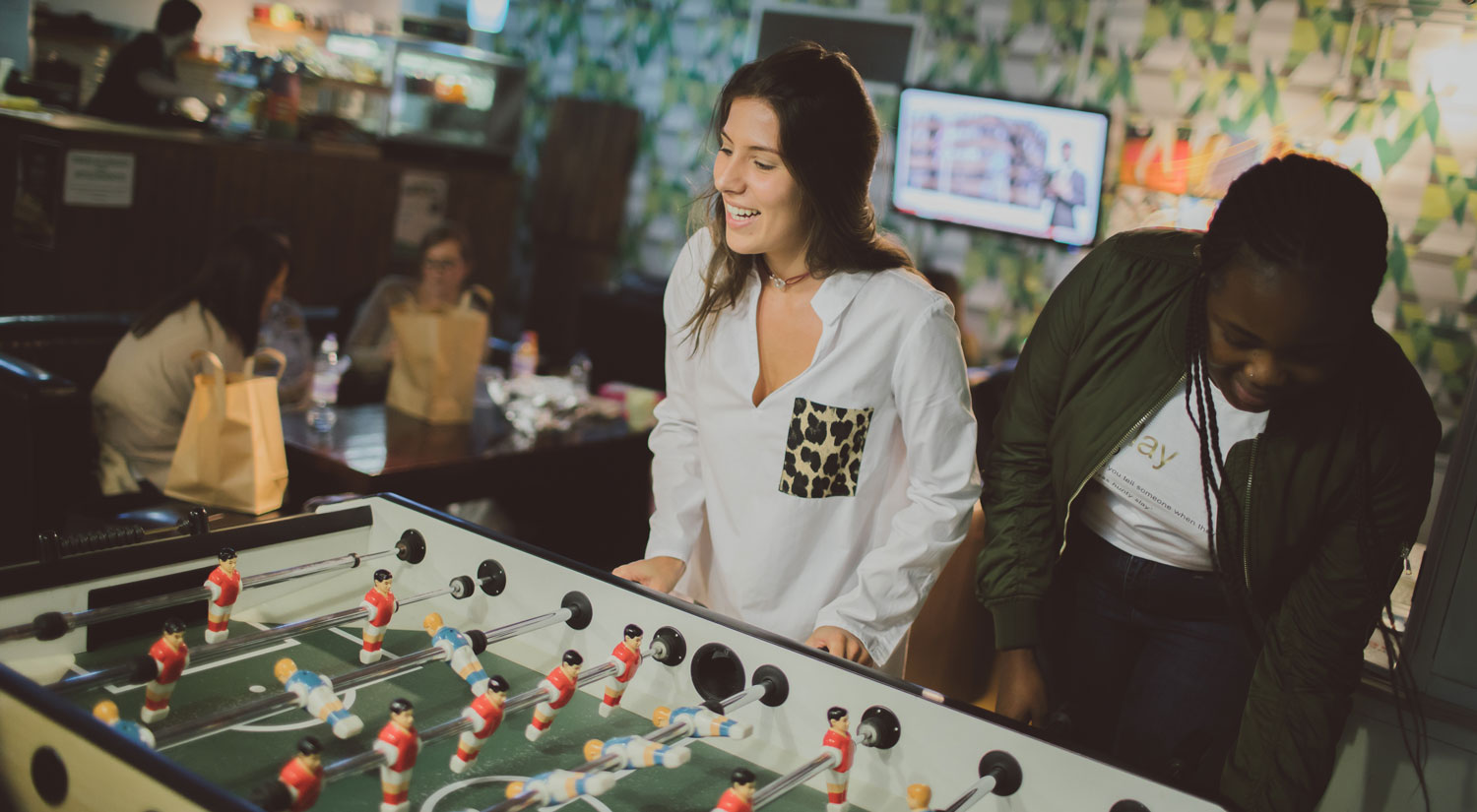 Two students playing table football in the Lounge)