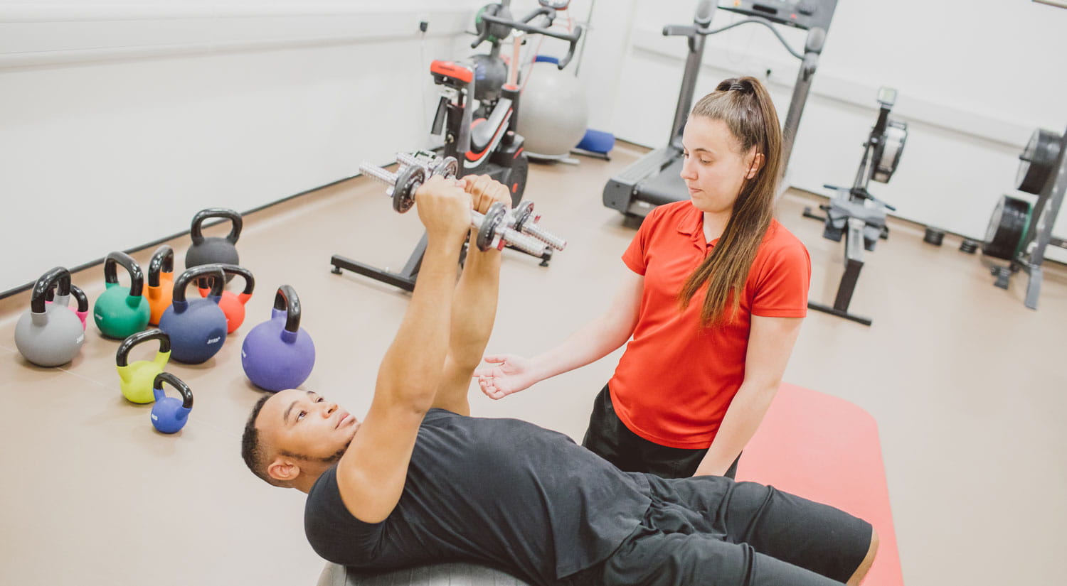 Student practising with another student in the clinic by advising of using weights to build strength