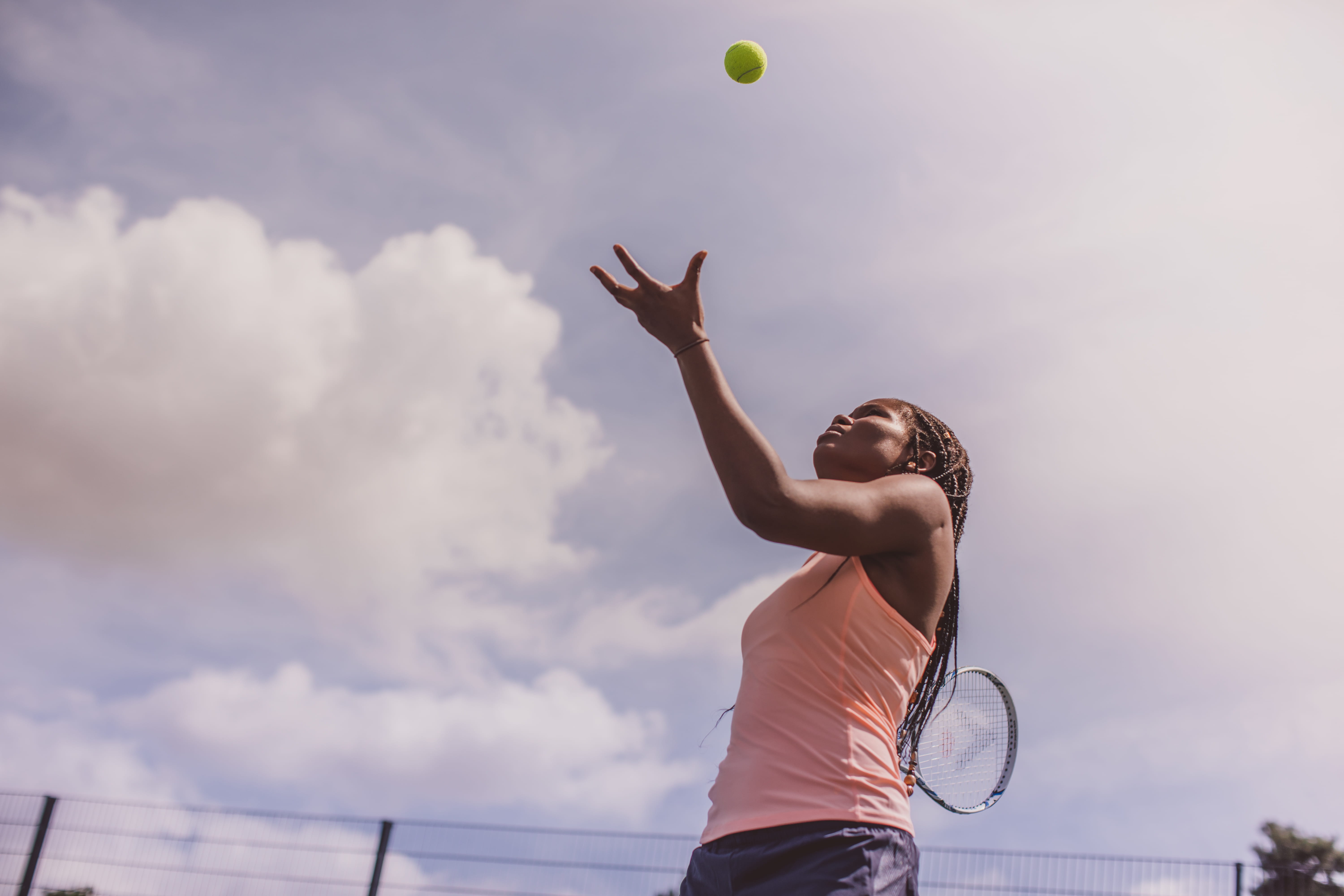 A female tennis player completing a serve