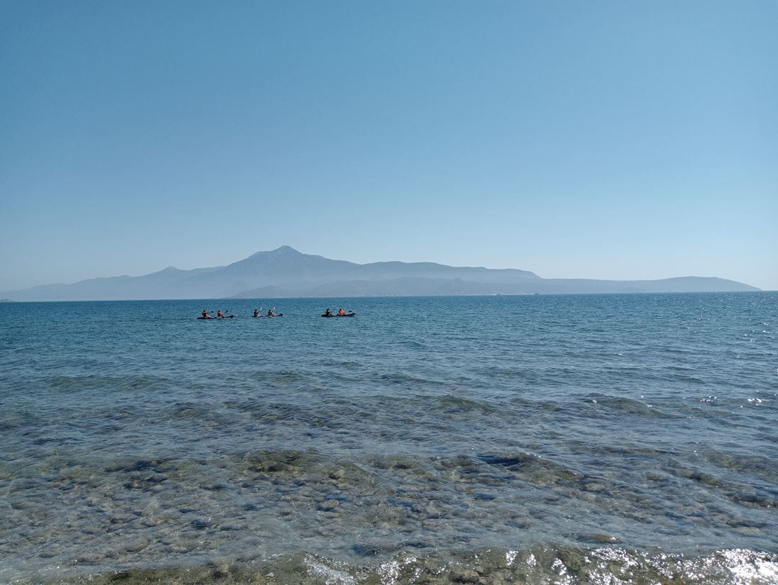 Three boats in the distance of the Greek coat, with a mountain in the faded background behind them