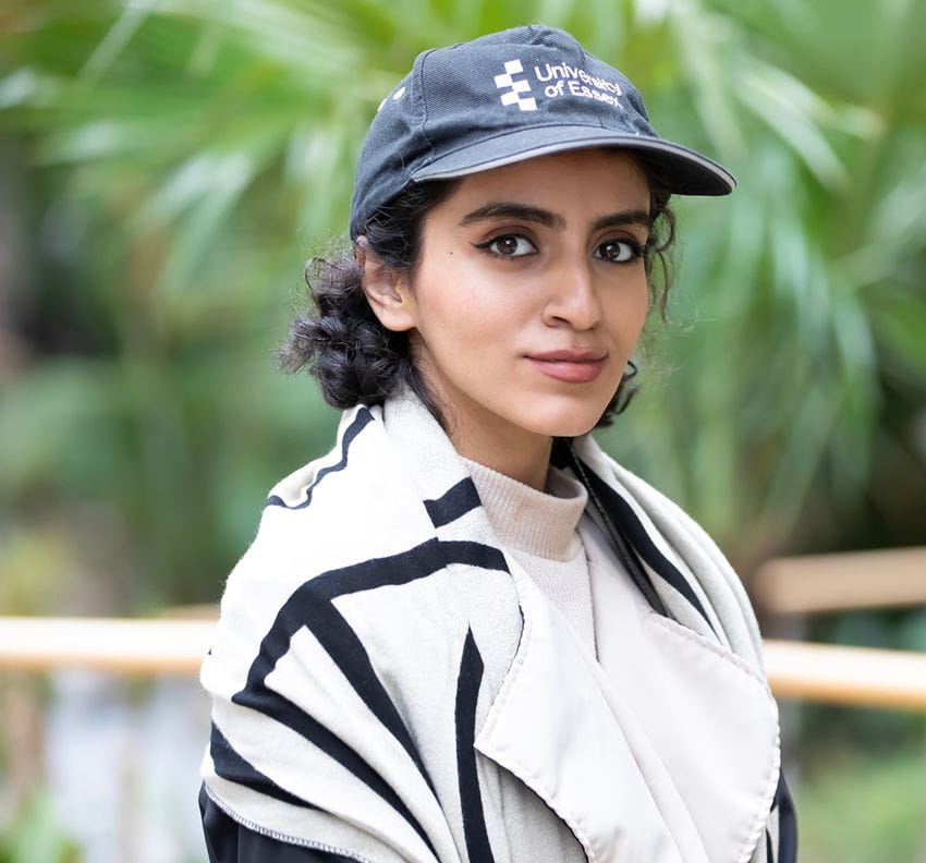 Student profile photo wearing and Essex branded cap in the EBS building