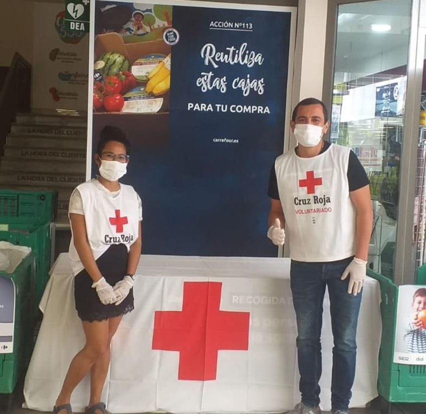 two people wearing masks collect food at a Red Cross food bank in Spain