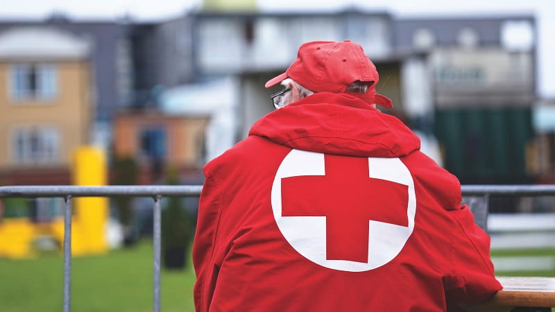 Man leaning on a face wearing a British red cross jacket uniform