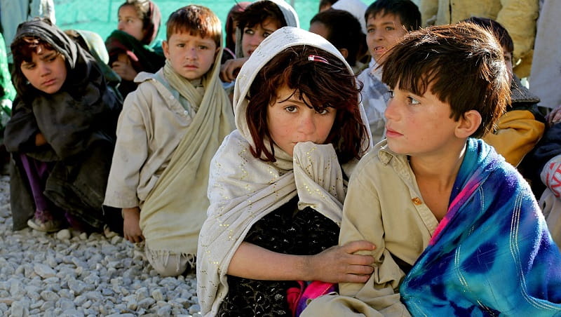 A line of small refugee children in a camp