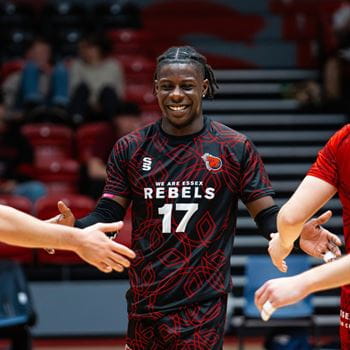 Male Rebels player walking low fiving other Rebels team players