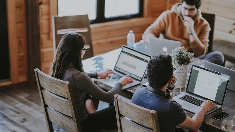 A group of people working at a table on laptops.