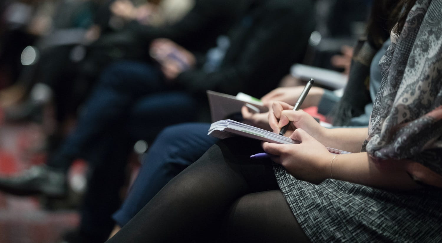 A row of journalists taking notes at a press conference.