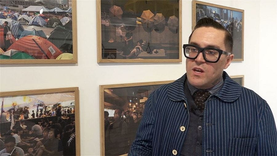 Academic Matt Lodder standing in a gallery with art in the background.