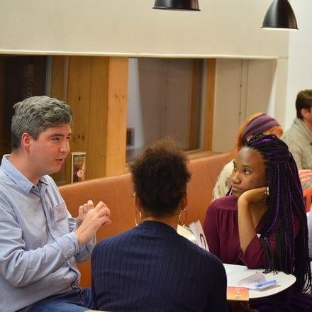 two students sit around a table discussing their career options with an Essex Alumnus