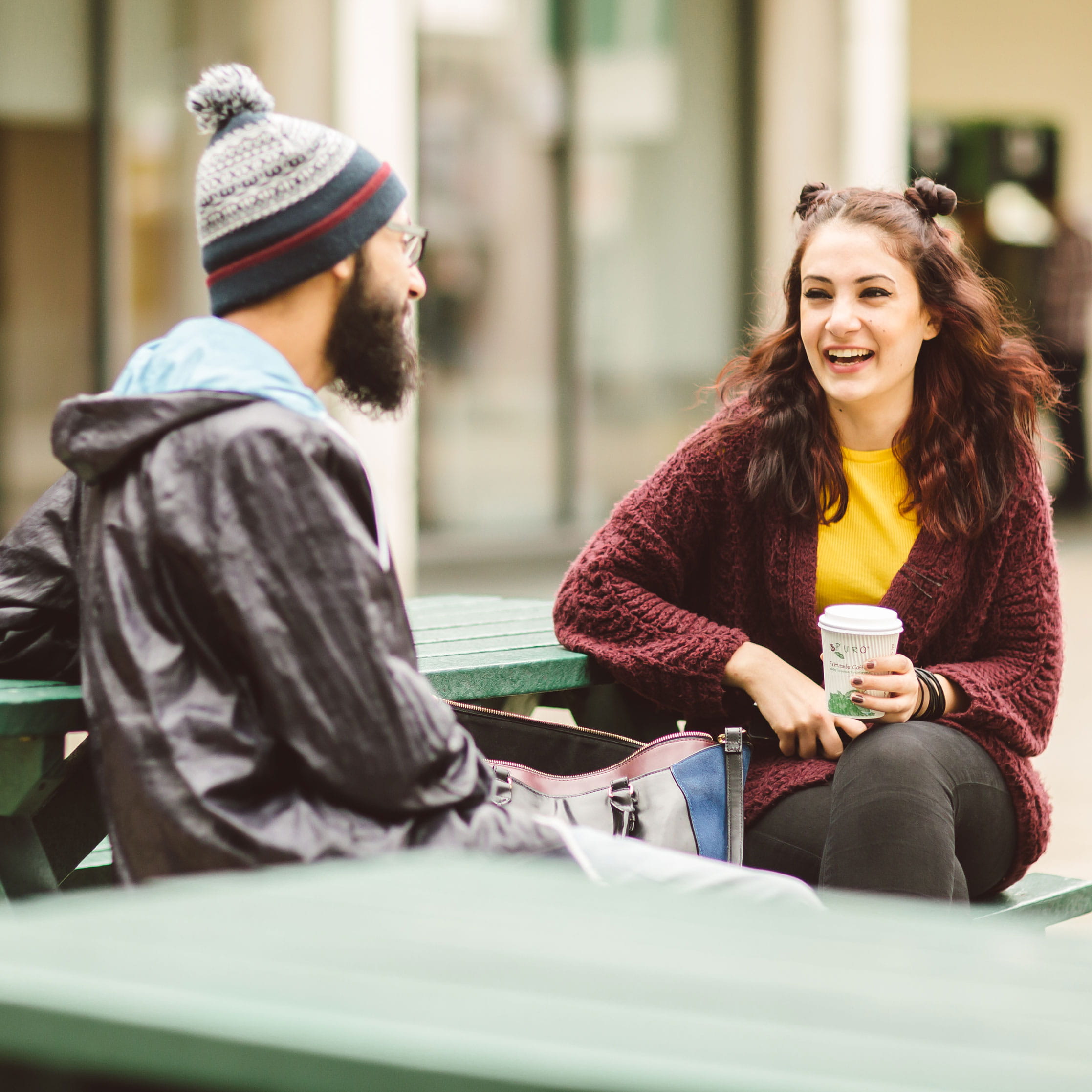 Two students sitting talking on a bench