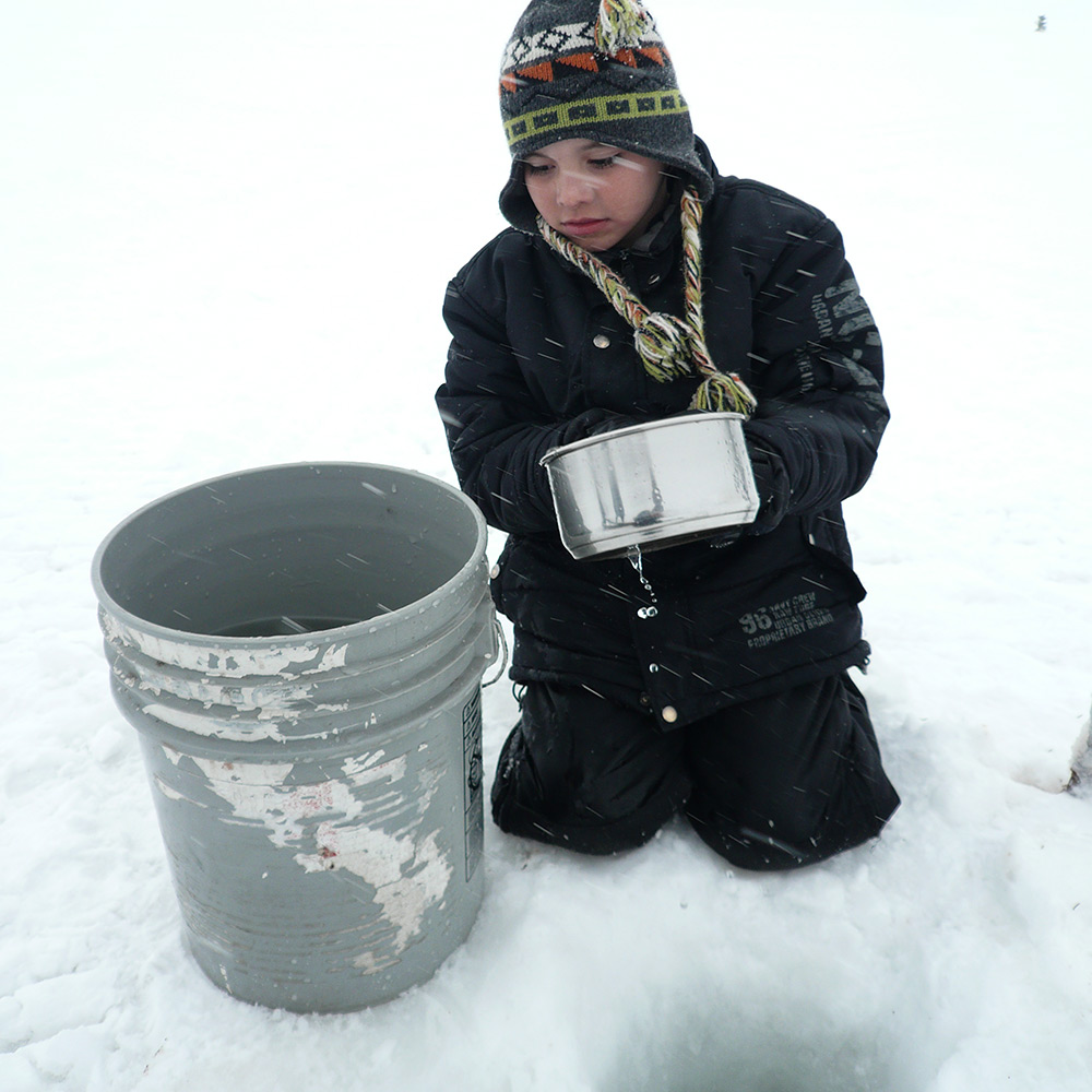 A child collecting fresh water from a frozen lake in Labrador, Canada