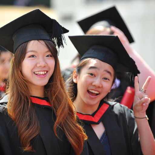 Two students wearing mortar boards at a graduation ceremony.