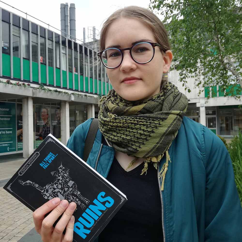 Ellinor Friström holding a copy of Ruins by Joshua Winnings