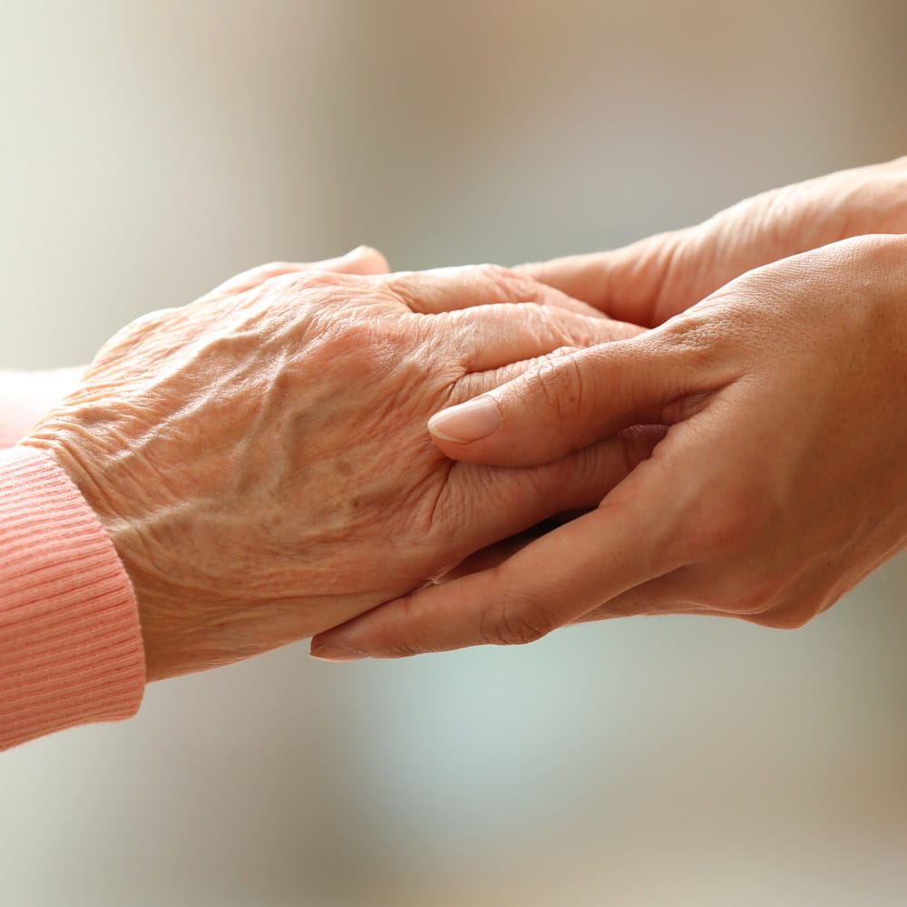 An older person holding the hands of a younger person
