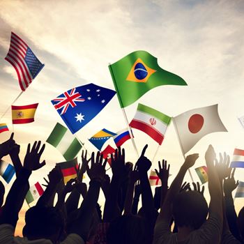 Lots of different national flags flying above a crowd.