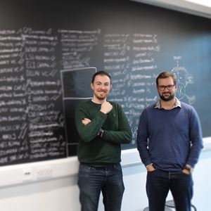 Chris Frogner and Ben Smyth stand in front of a chalkboard