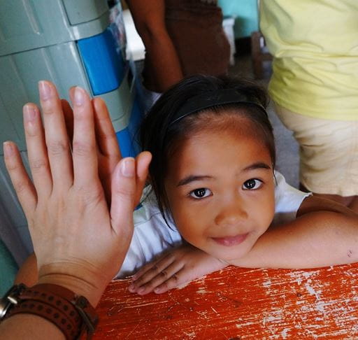 Young girl placing hand against volunteer