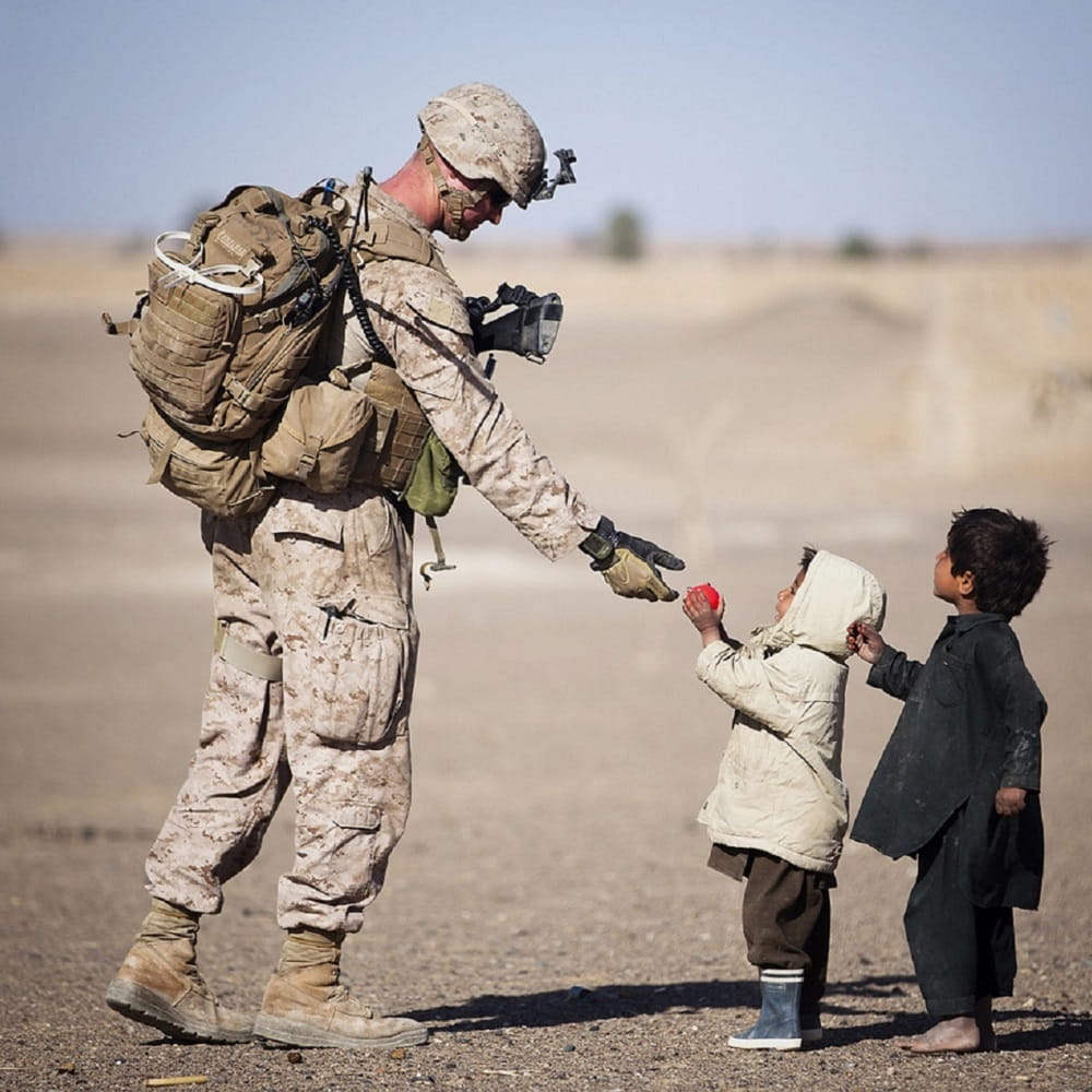international relations conflict war army soldier gives aid to two small children