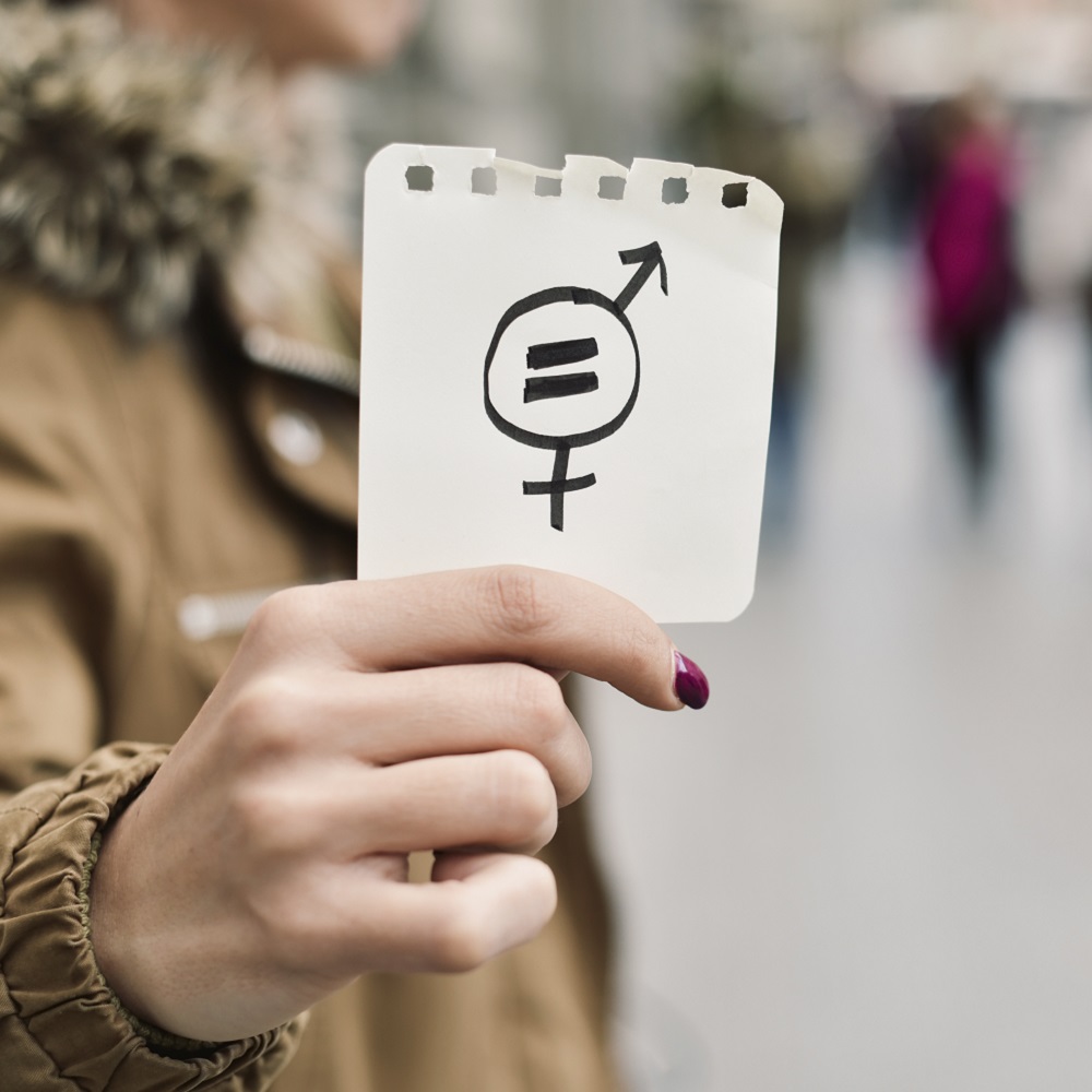 A person holding up a piece of paper with the gender signs on.