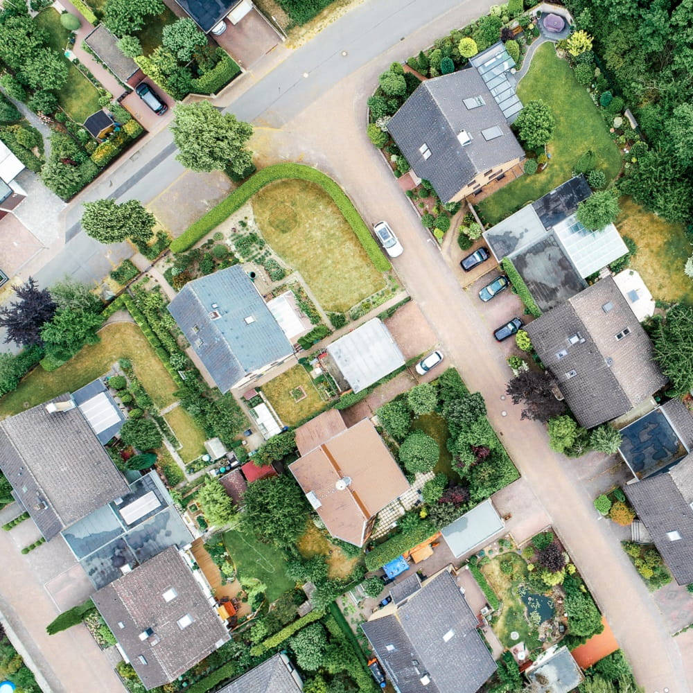 Aerial view of a suburban street with trees and houses.