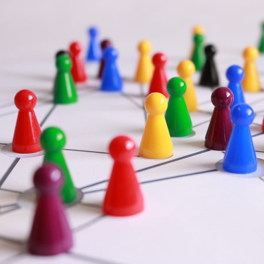 Lots of different coloured plastic chess pieces on a board with straight pencil lines  connecting them.