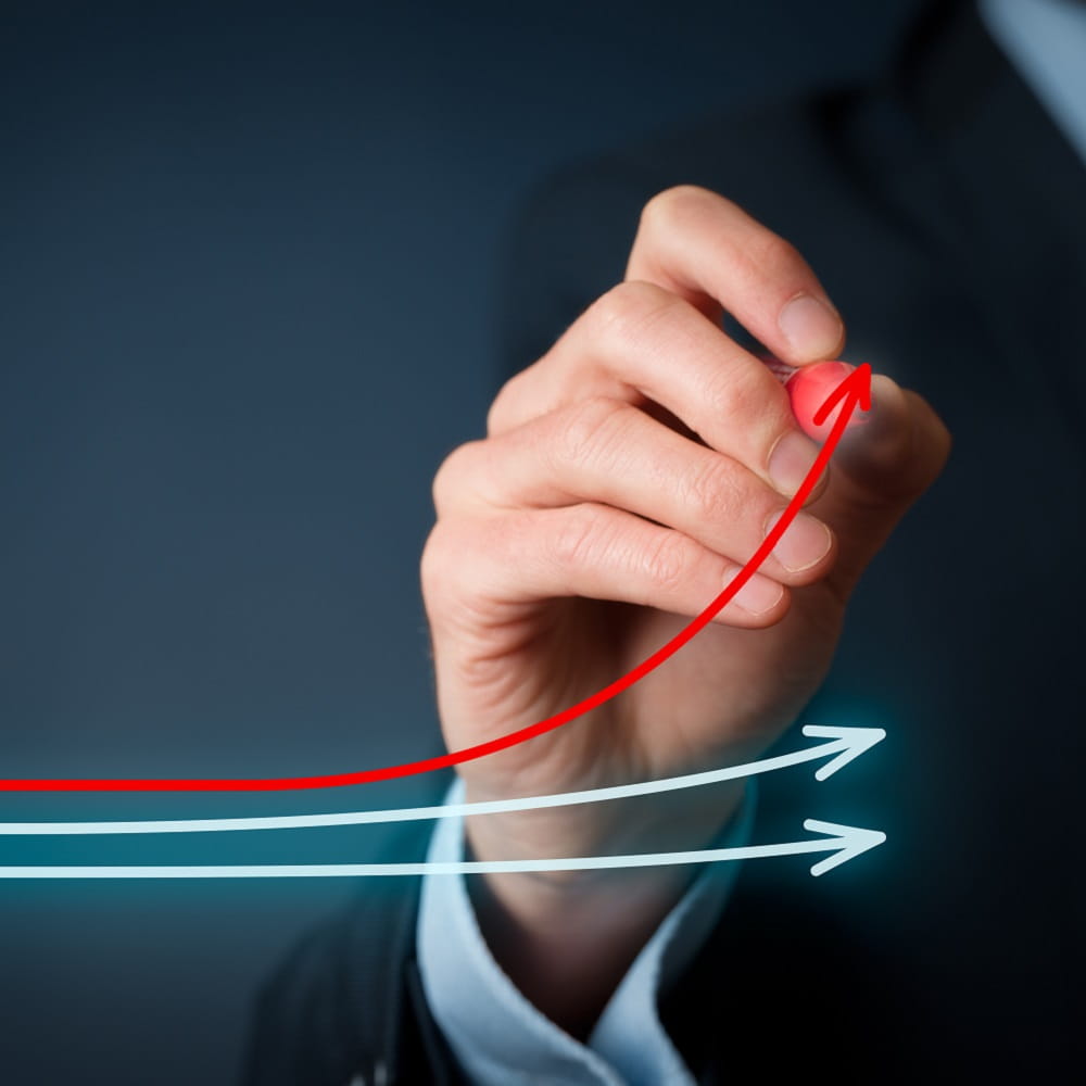 A man wearing a business suit drawing red and blue arrows which point upwards to signify productivity.