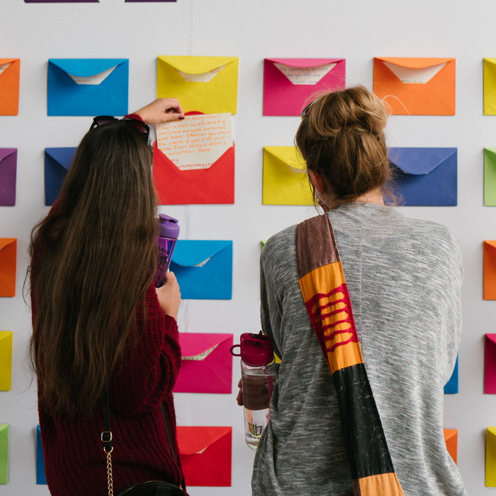 two people looking at letters from students in coloured envelopes