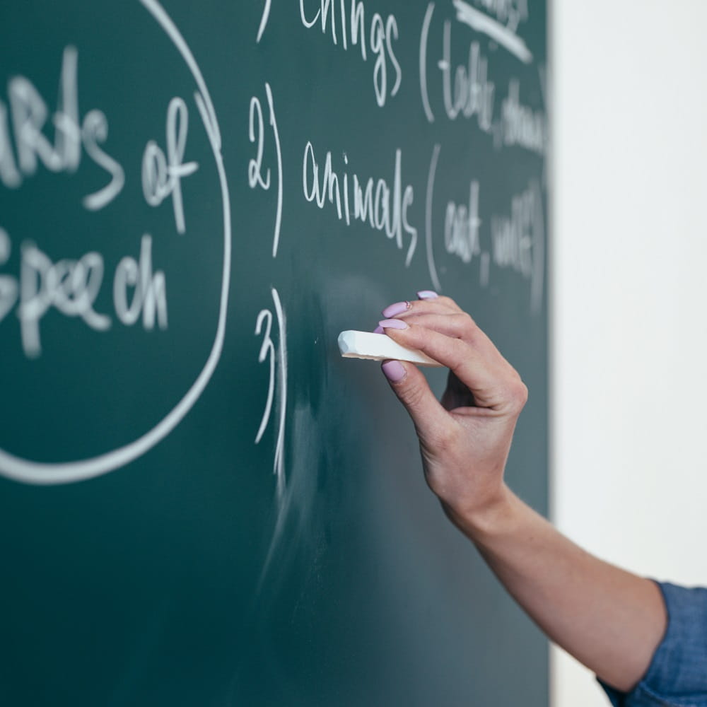 An English language teacher writes on a chalk board.