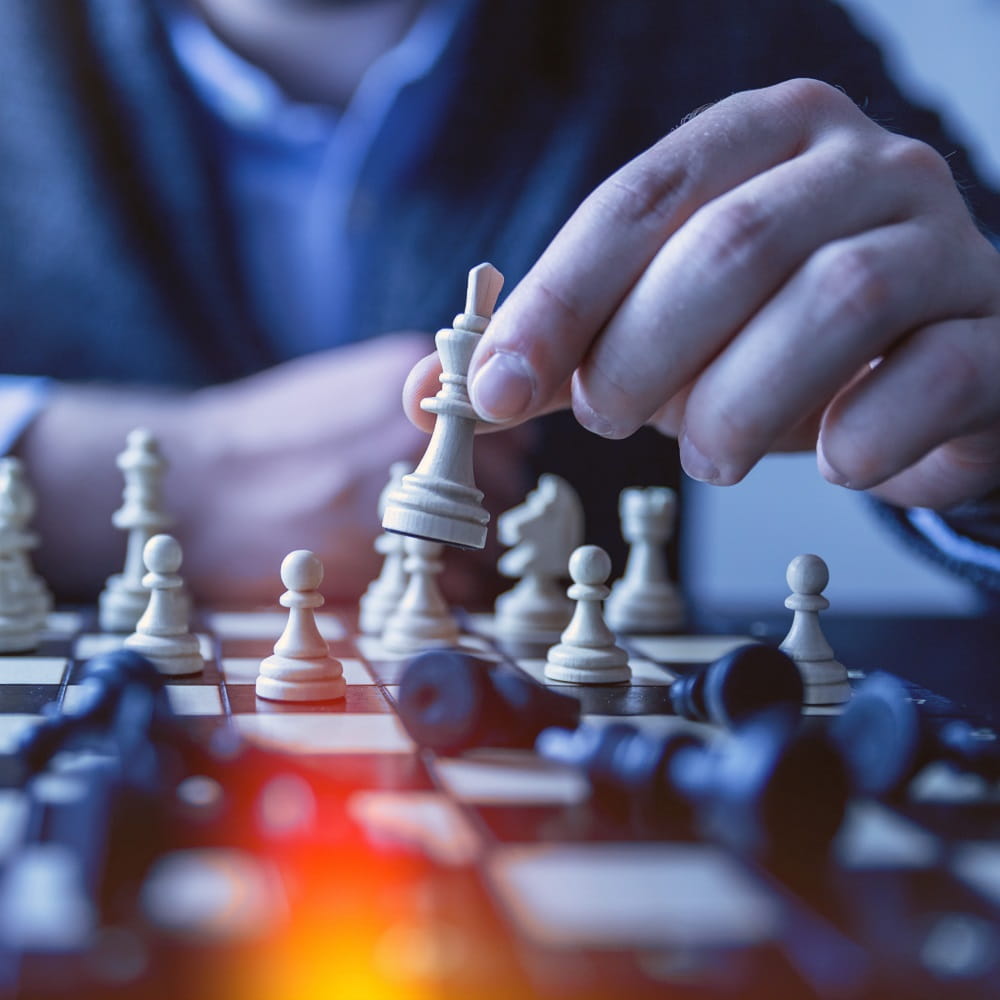 A close up of a man playing chess, deciding which pieces to move.