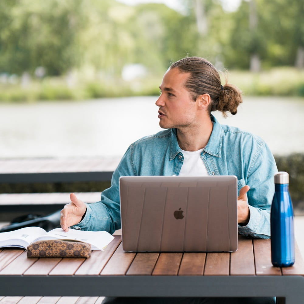 Person sat using laptop outside whilst talking
