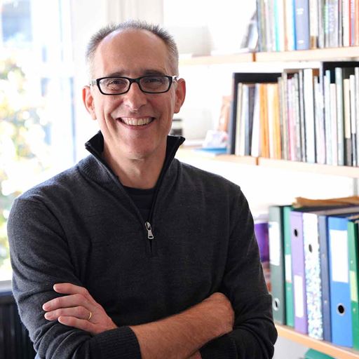 Professor Jonathan Lichtenstein with his arms folded wearing a dark sweater and dark-rimmed glasses