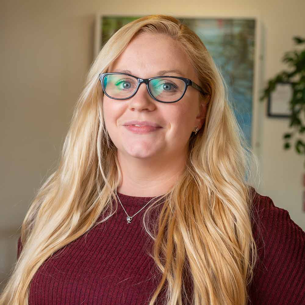 Catherine Duggan, wearing a maroon-coloured top and glasses