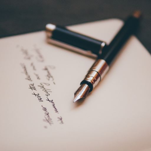 A fountain pen balanced on a piece of paper with writing on.