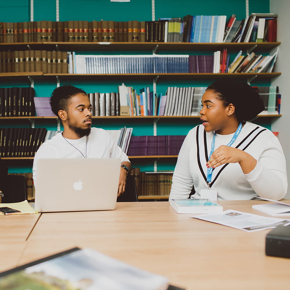 Two students in a library in discussion 