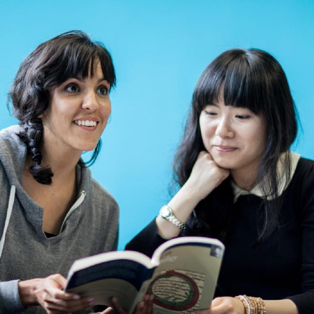 Two women reading a book.