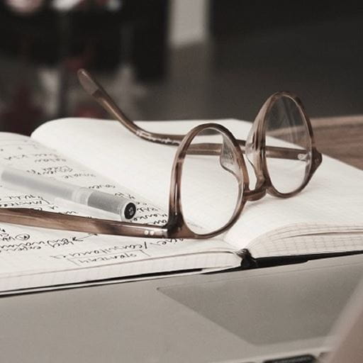 A pair of glasses resting on top of an open notebook.