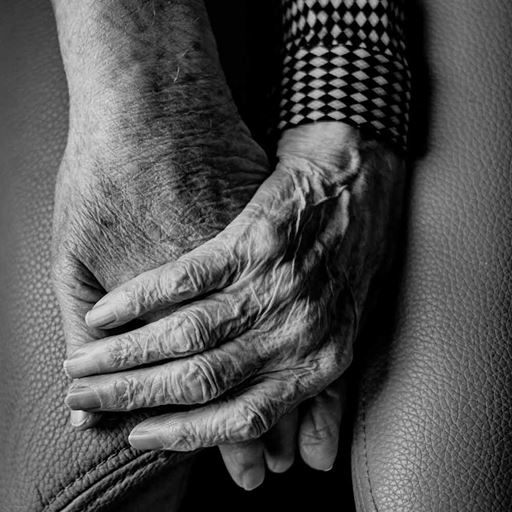 Two hands, one of an elderly person photographed in black and white