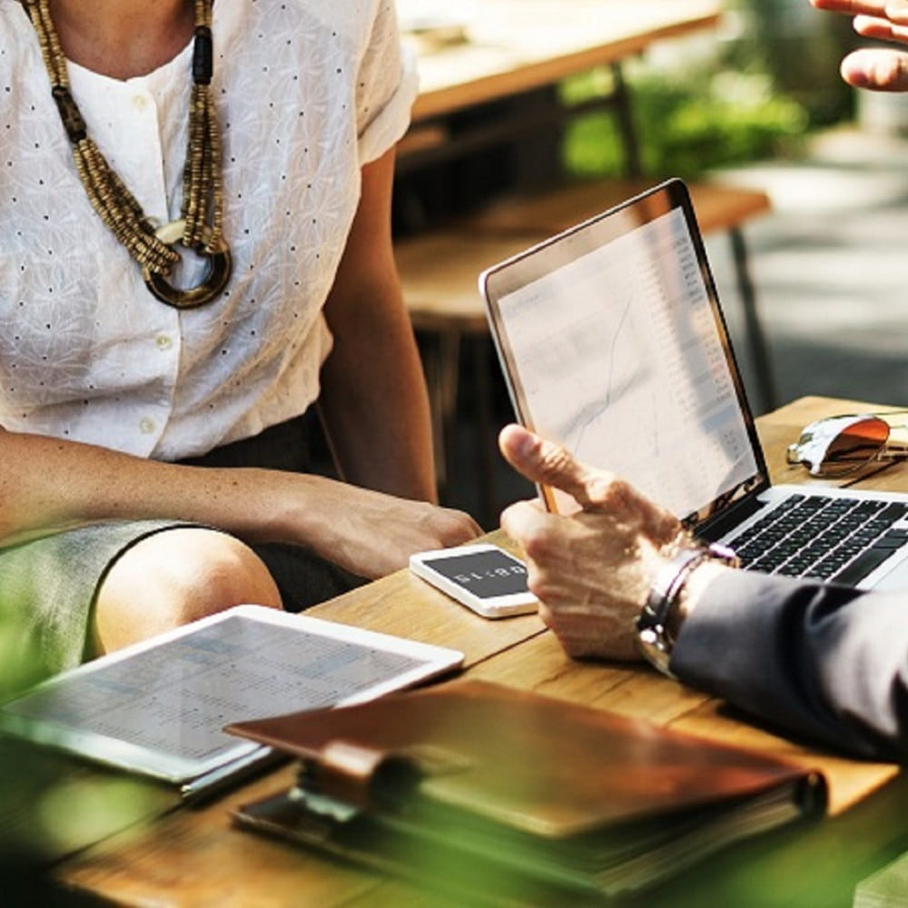 Two members of staff sat at a desk using a laptop.