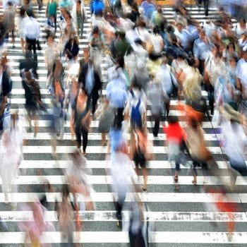 A blurred shot of lots of people walking in the city.